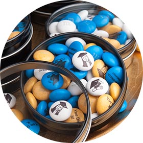 Canister of yellow, blue, and white M&amp;Ms with a graduation theme