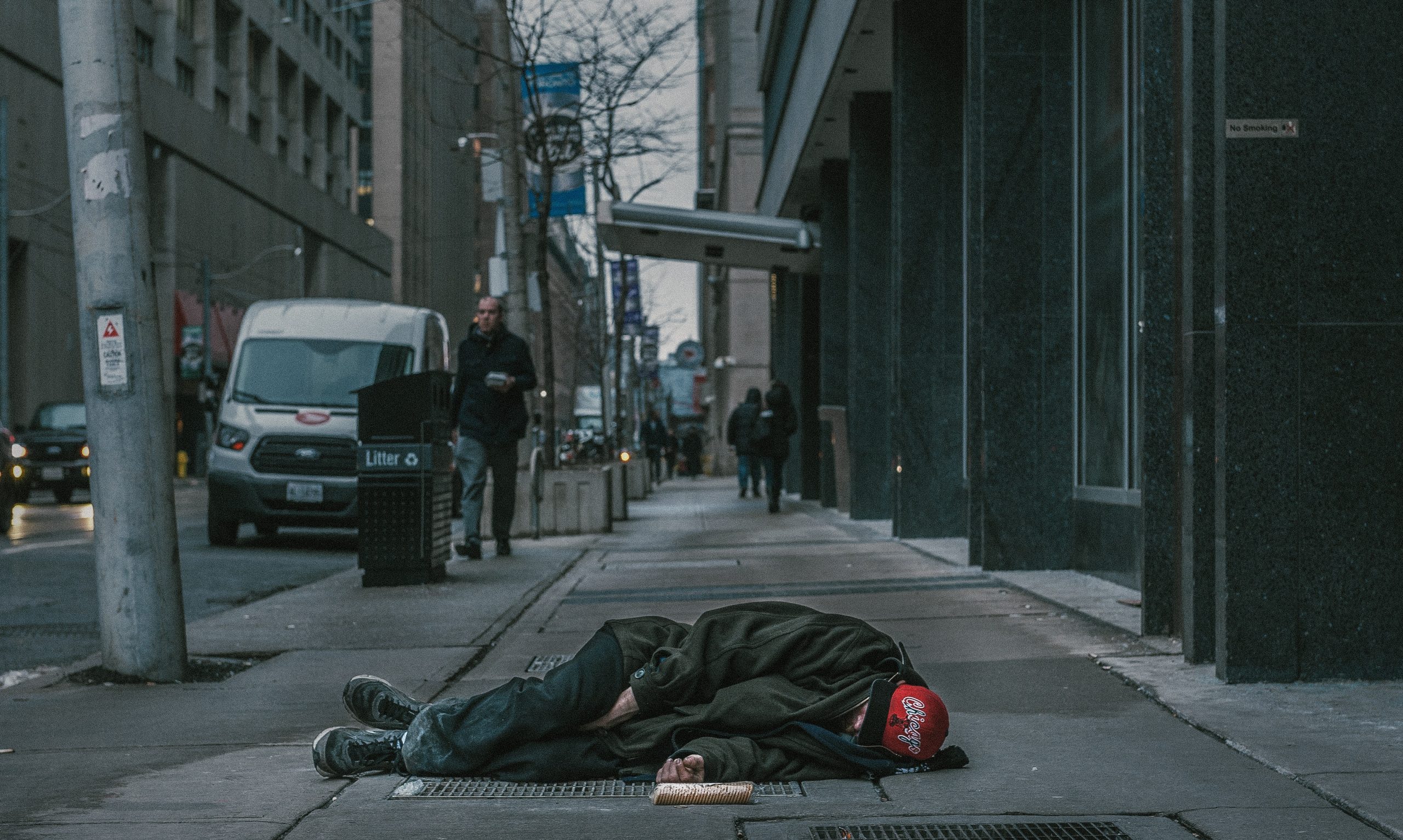 Homeless person sleeping on the sidewalk.