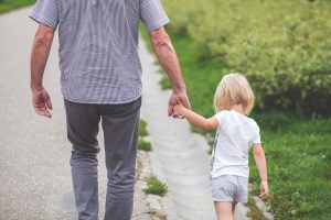 Dad holding child's hand as they are walking
