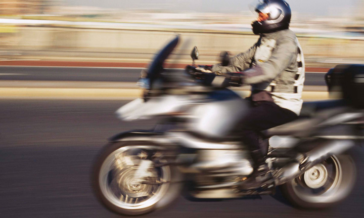 A man wearing a helmet on a moving motorcycle on the road