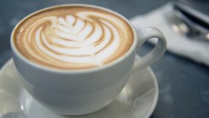 A cup of cappuccino with a leaf design.