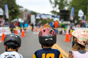 Three children wearing helmets at an obstacle course.