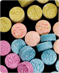 MDMA/Ecstasy pills in the colours pink, peach, blue, and yellow.