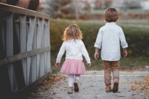 Two children walking across a bridge.