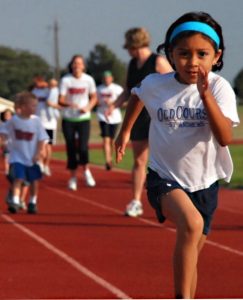 A girl running on a track field.