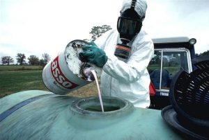 A USDA employee pouring hazardous chemicals into a storage container.