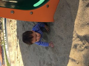 An infant playing in the sand.