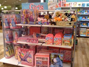 Store shelves filled with pink and purple colors and girls’ toys.