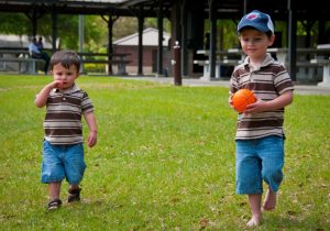 Two boys in a backyard, one with autism is holding a small basketball