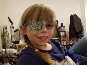 Little girl with glasses and a patch over her right eye