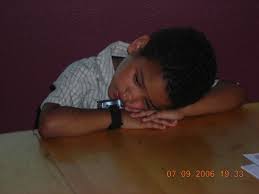 Young boy laying his head down on a table.