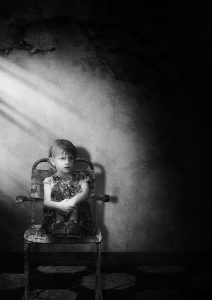 Young girl sitting alone on a chair looking sad