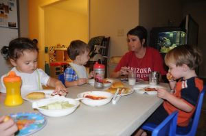 Teacher eating with four children.