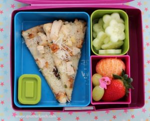 Lunchbox with a pizza slice, cucumber slices and mixed fruit