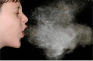 Young boy coughing showing a mist of droplets coming out of his mouth