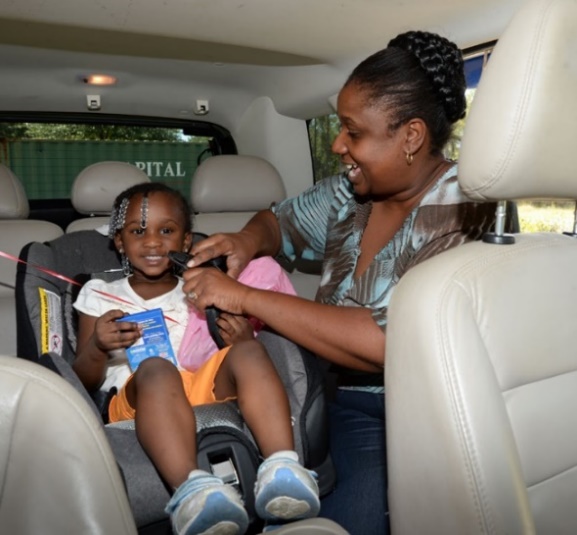 Caregiver strapping a young child into a carseat.