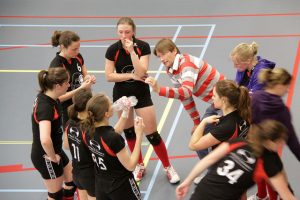 Women's volleyball team on a time out being instructed by their coach