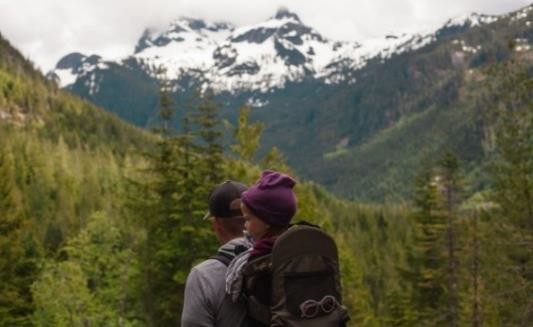 Adult and child in backpack on a mountainous hike.