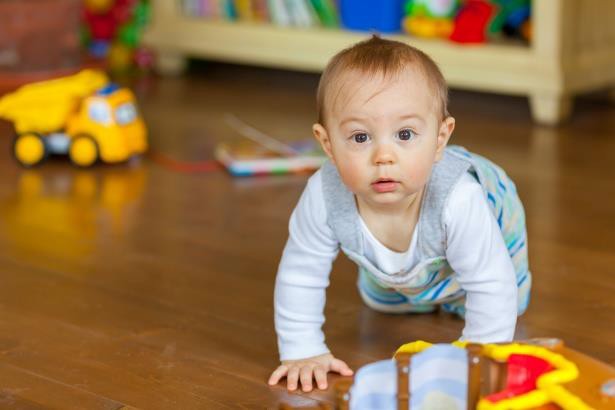 An infant crawling on the floor.