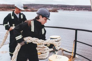 students on board a ship holding rope.