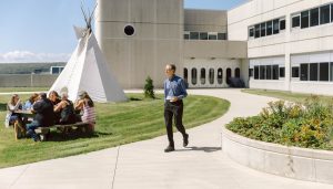 group of students at a picnic table outside on NSCC campus with a tipi in the background.