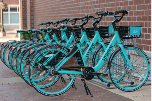 A row of bright blue bicycles next to a brick wall.
