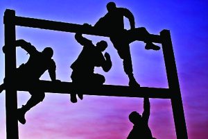 Four soldiers climbing an obstacle course structure at dusk.
