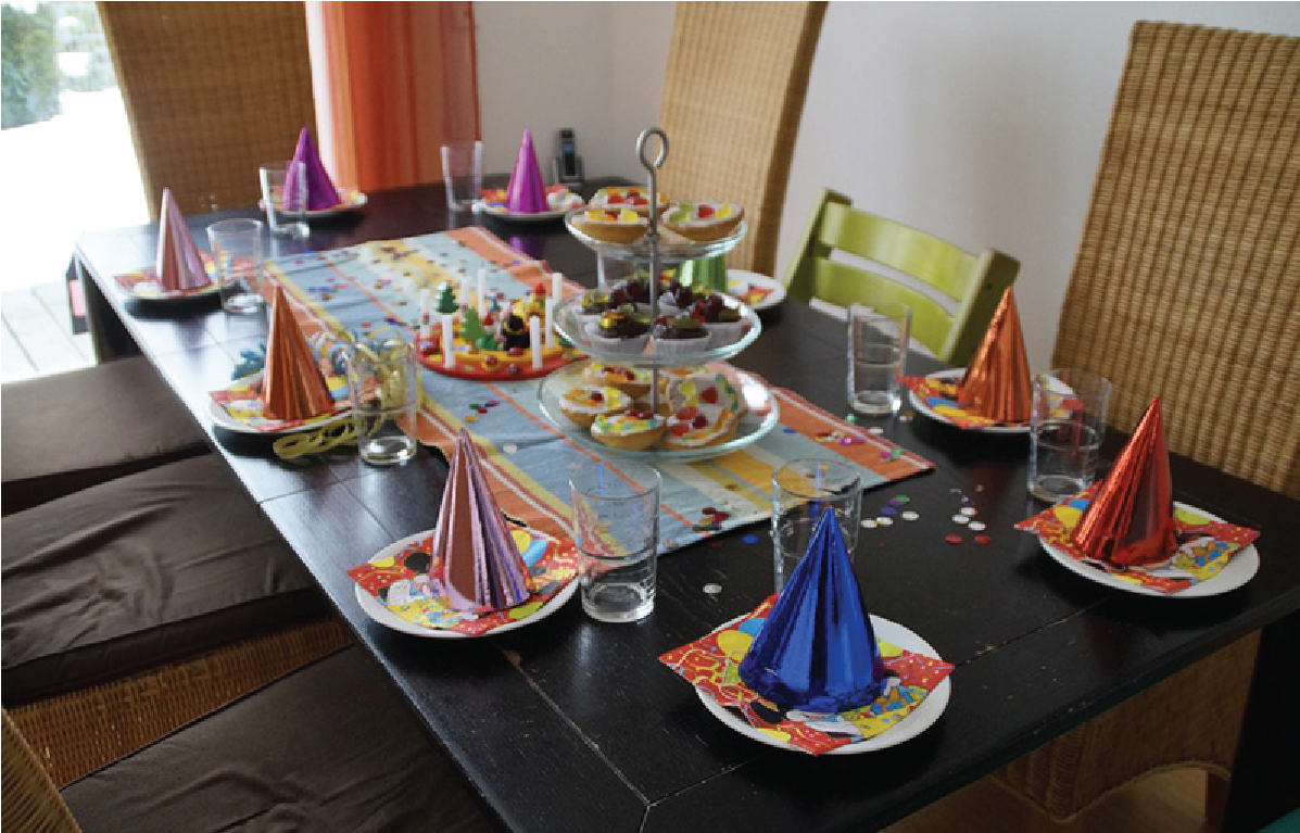 A table is prepared for a birthday party with party hats set in front of each seat.