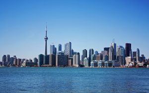 View of downtown Toronto from the water. CN Tower surrounded by tall buildings with Lake Ontario in the fore ground.