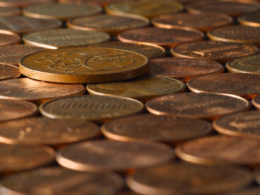 Photograph of many coins laid down on a surface, some with heads shown up and some with tails shown up.