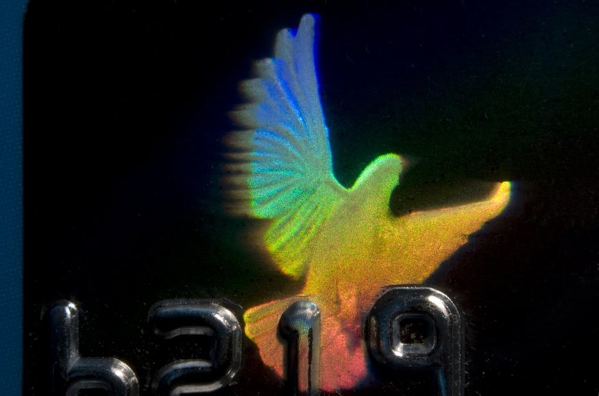 The image shows a rainbow-colored hologram of a bird on a credit card.