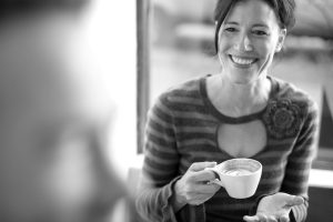 Woman sitting with coffee cup wearing a stripped sweater.