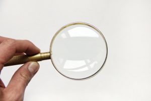 A hand holding a magnifying glass.