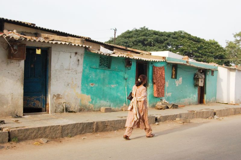 A woman in India is shown from behind walking down the street.