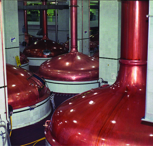 A picture is shown of four copper-colored industrial containers with a large pipe connecting to the top of each one.