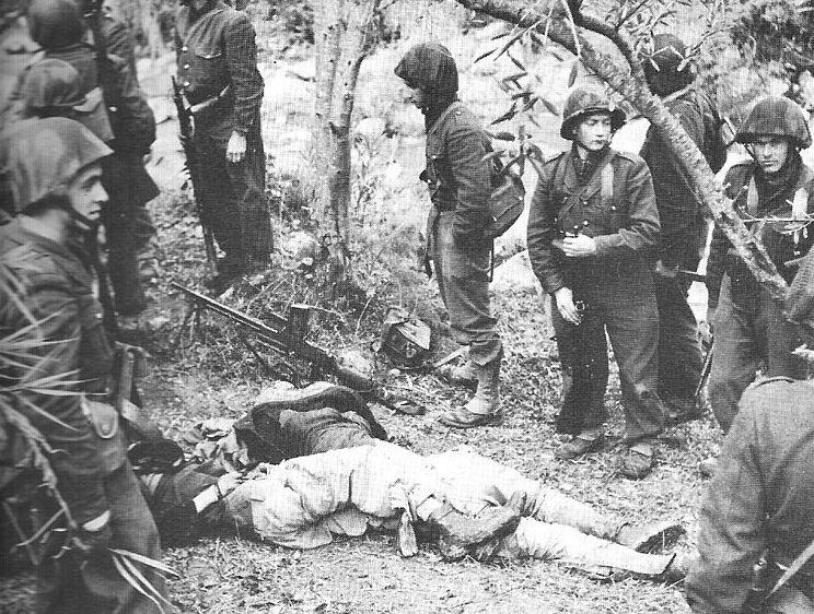 French soldiers standing nonchalantly next to the bodies of Algerians.