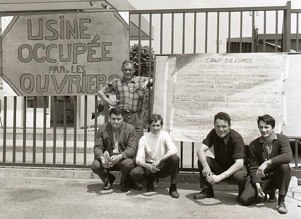 A group of workers proudly posing in front of their occupied factory.