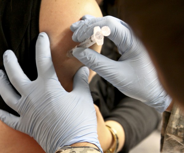A nurse putting a needle into a person's arm.
