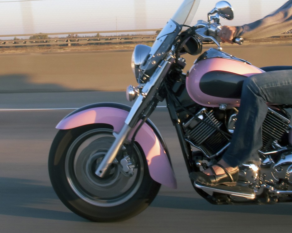 A woman riding a pink motorcycle.
