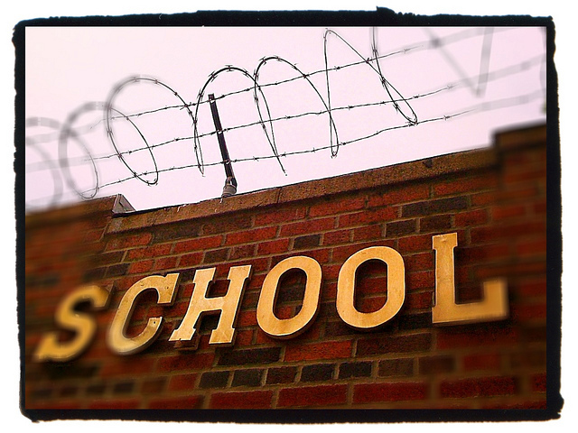 A school wall topped with barbed wire fence.