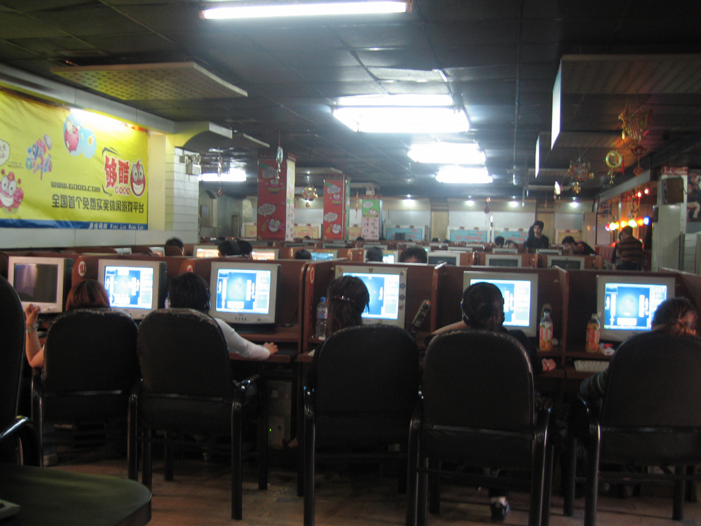 Rows of people at computers in a café
