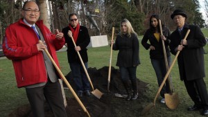 A group of people holding shovels around a hole in the ground