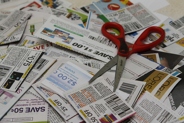 A pile of coupons with a scissor resting on them.