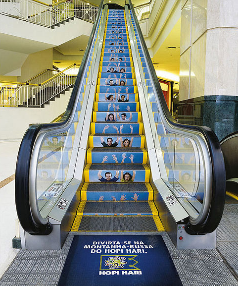 An escalator with an ad for a roller coaster